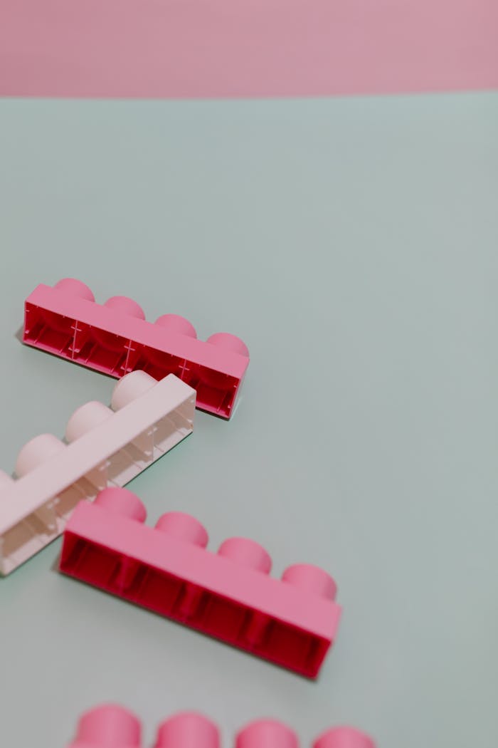 Close-up of pink and white toy building blocks on a pastel background, offering a playful and creative composition.