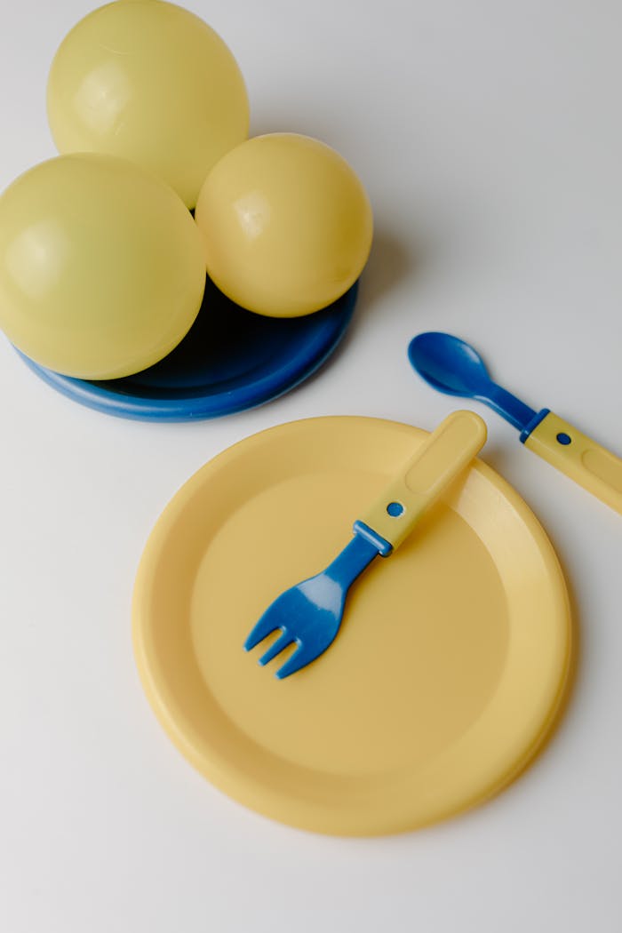 Colorful children’s dinnerware set with yellow plates and blue cutlery, perfect for playful meals.